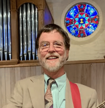 photo of Keith Atwater in front of a stained glass window